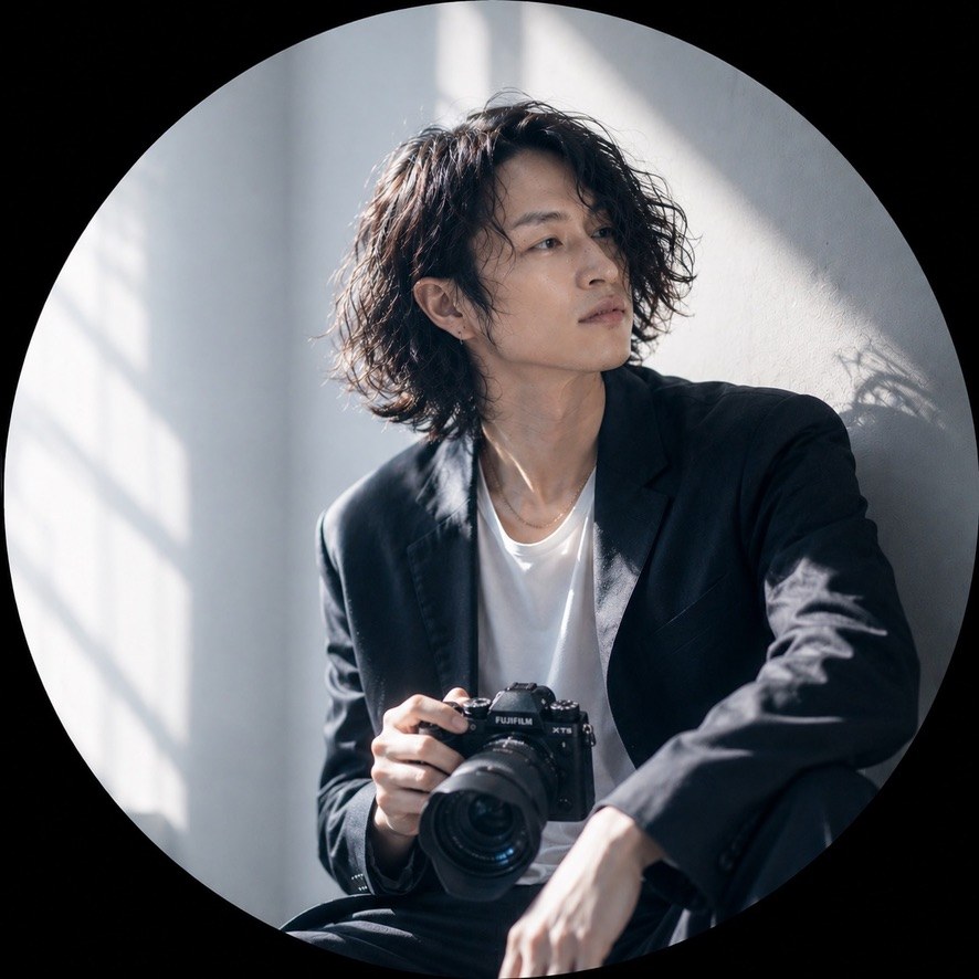 カメラを手に窓辺に座るyuyaのポートレート
